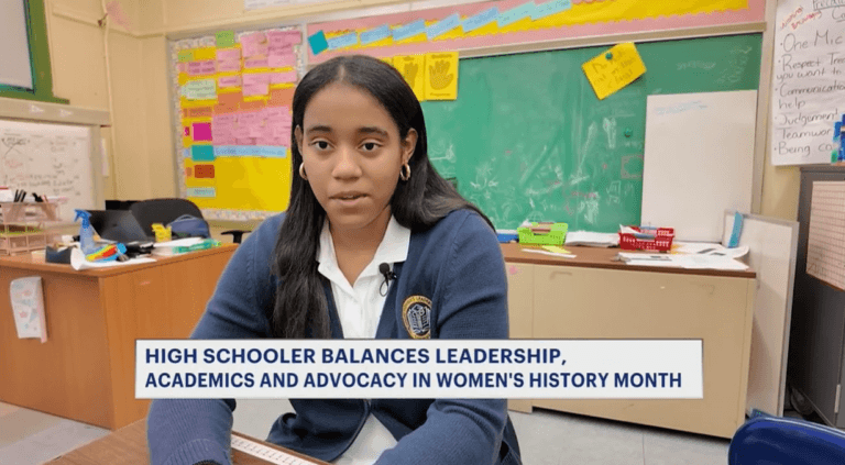 A Young Women's Leadership School student sits at a desk in a classroom with colorful notes on the walls. News headline text about her balancing leadership, academics, and advocacy is shown on the bottom.